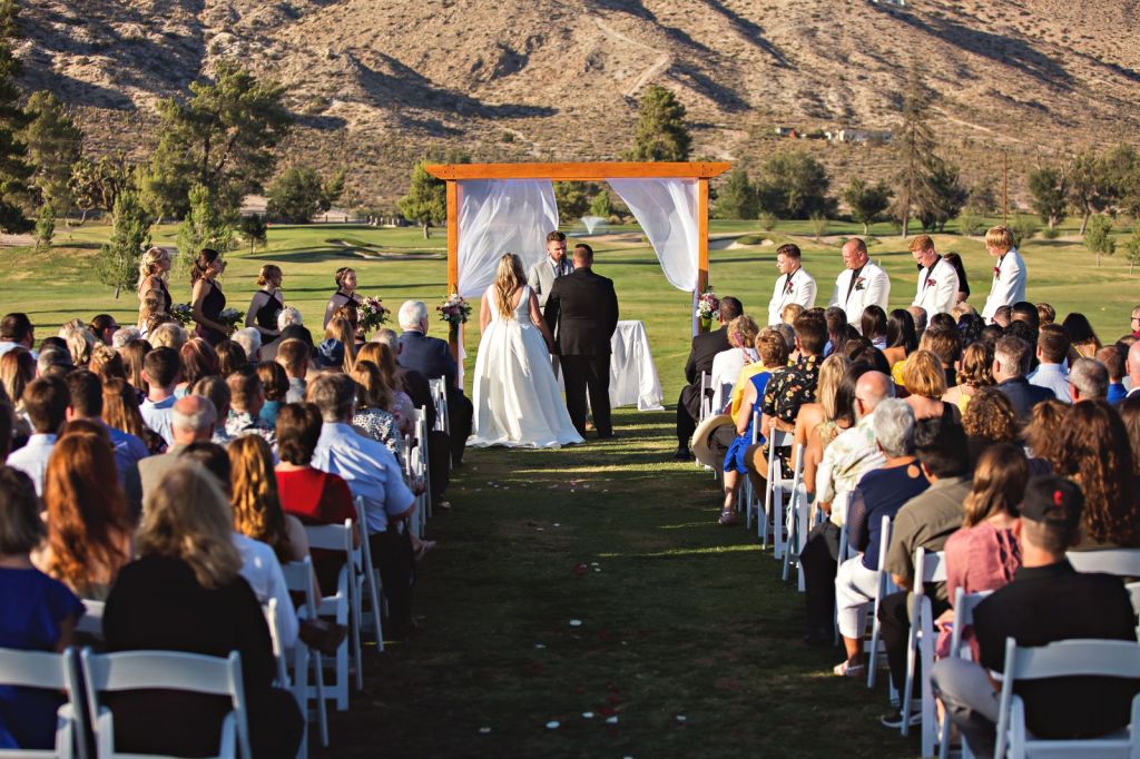 Looking directly down the aisle toward the couple, this image captures a touching moment at a wedding ceremony hosted at the course. 