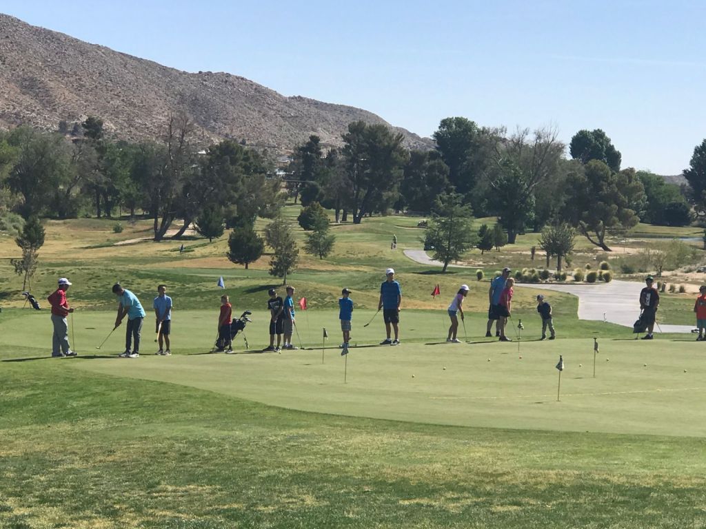 This image features a group of golfers at a clinic, lead by the staff at Hawk's Landing.